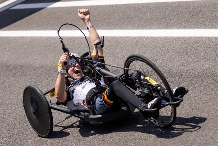 Hand cyclist celebrates after crossing the finish line