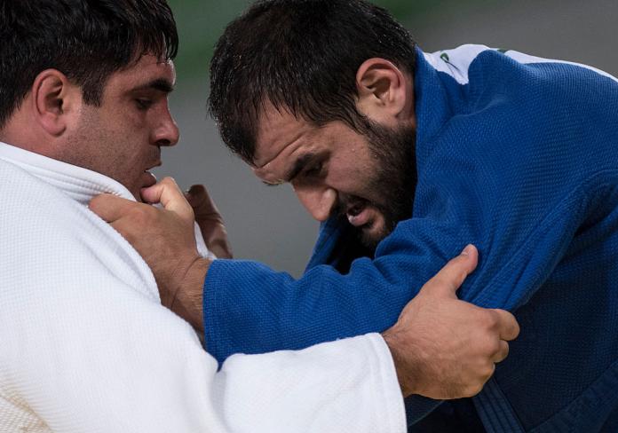 Two male judokas hold on to each other uniforms