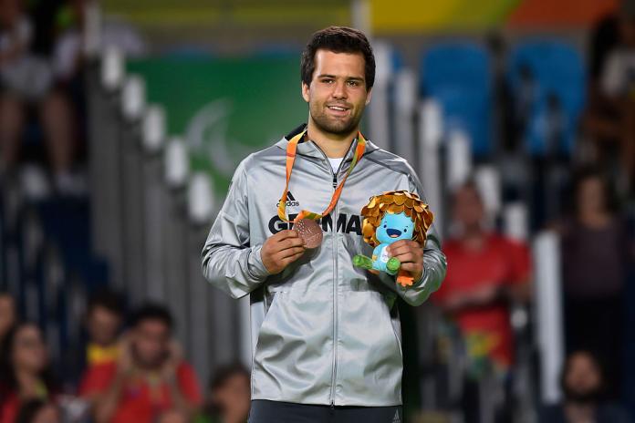 German male judoka smiles with bronze medal and Rio 2016 mascot