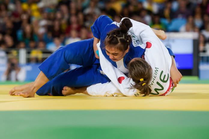 A women pins down her opponent on the judo mat