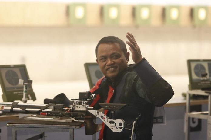 pria memegang pistol melambai di kerumunan