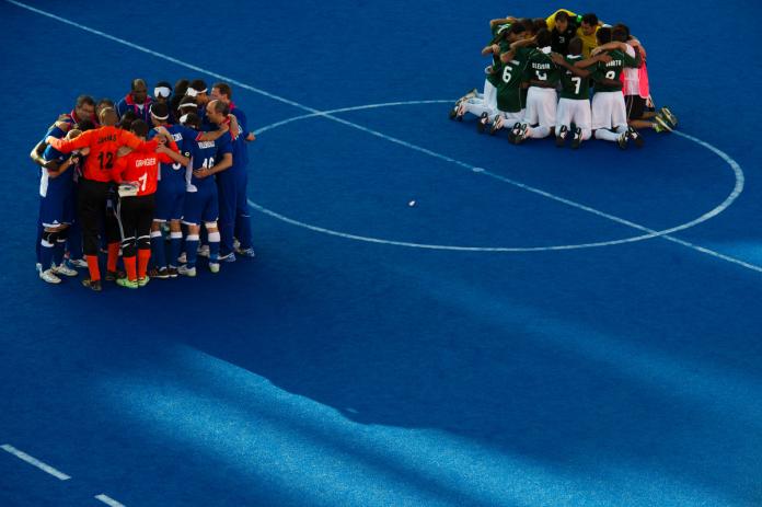 Two teams huddle separately on the pitch