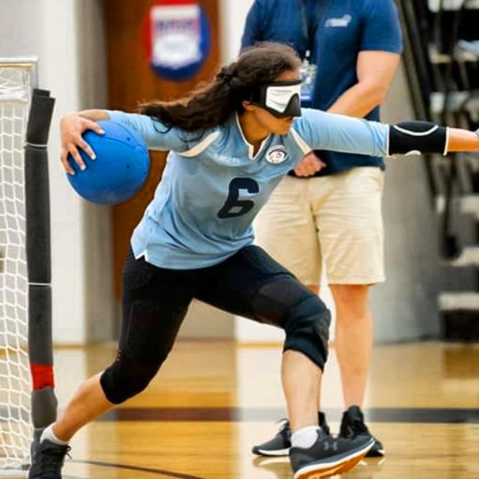 A female goalball player ends to throw the ball