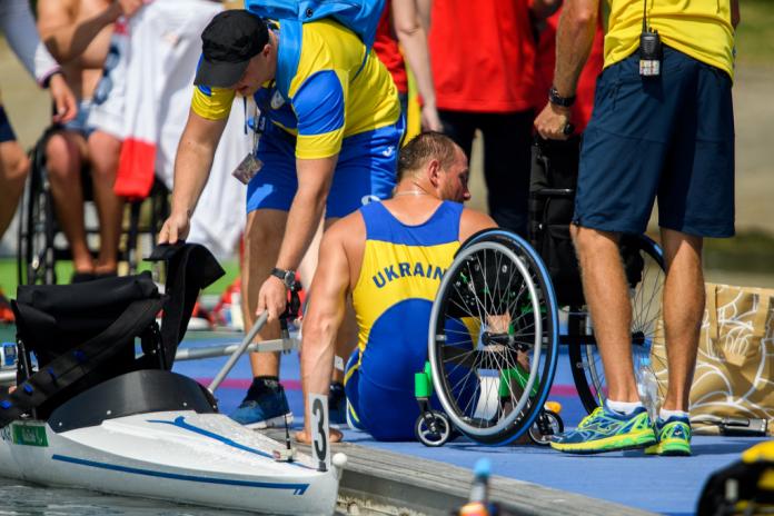 Man gets off wheelchair and waits as his rowing boat is prepared