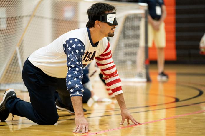 Male goalball player touches the floor to orient himself