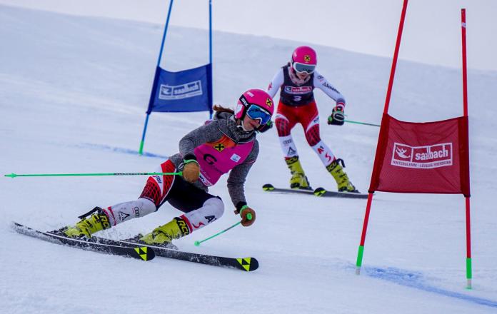 A female skier following her guide in a Para alpine skiing race