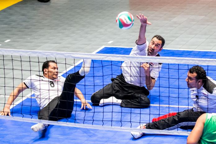 Male sitting volleyball player spikes the ball