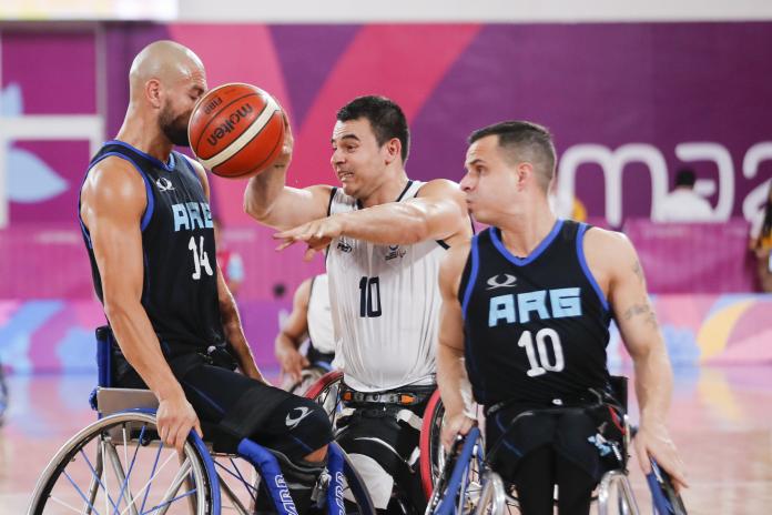 Colombian wheelchair basketball player Jose Leep tries to dribble past two Argentine players