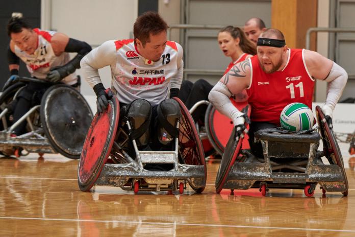 Denmark's wheelchair rugby player Mark Peters advances with the ball against a Japanese defender