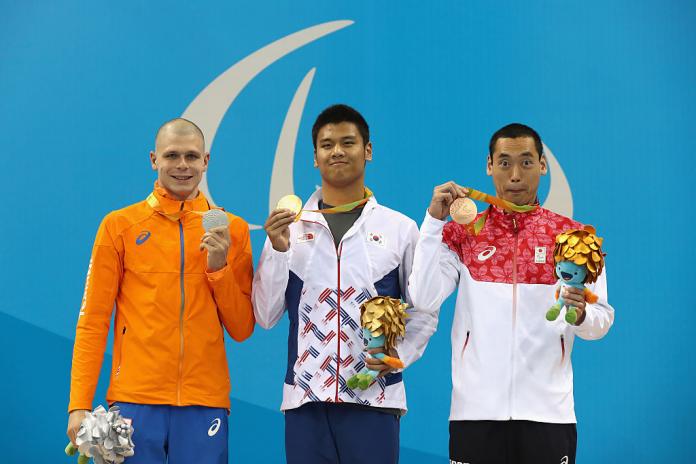 Three male swimmers on Paralympic podium with medals