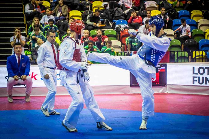Male taekwondo fighter kicks his opponent