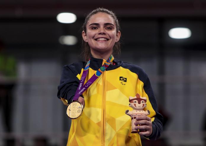 Woman smiles holding medal and mascot gift