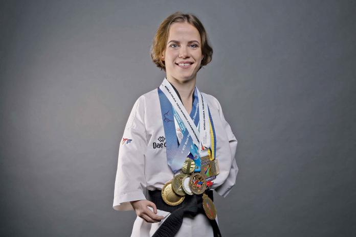 Female taekwondo fighter smiles with lots of medals around her neck