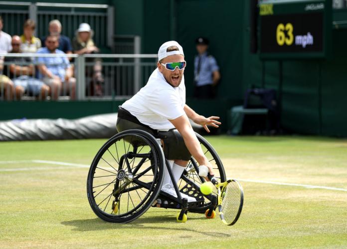 Man in wheelchair does backhand hit in wheelchair tennis