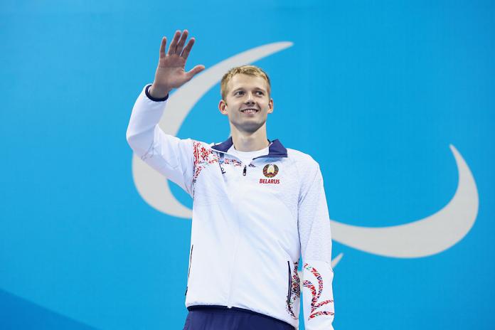 Belarusian male swimmer on Paralympic podium waving at crowd