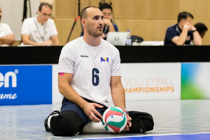 Sitting volleyball male holds ball preparing to serve