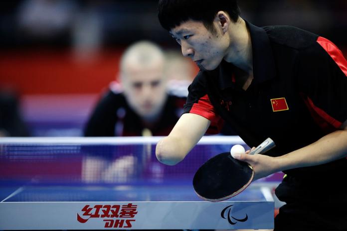 Chinese man with right arm impairment serves the ball in table tennis