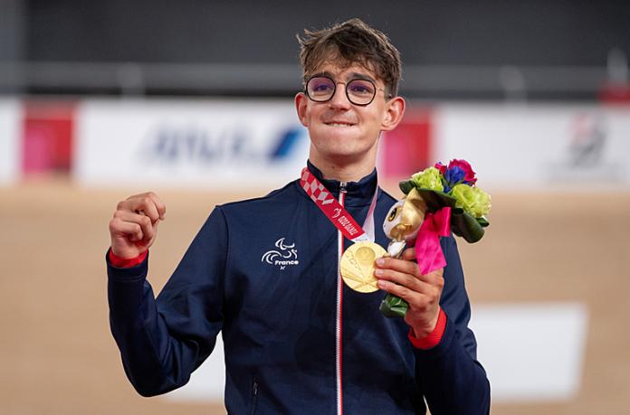 Alexandre Leaute holding his gold medal and mascot on the podium