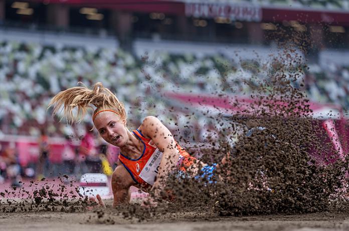 A woman falling in a sand pit in a long jump competition