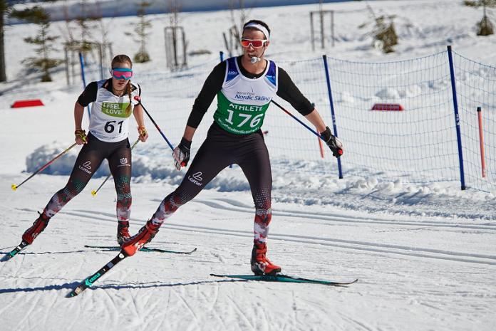 A female Para cross-country skier following her male guide during a competition