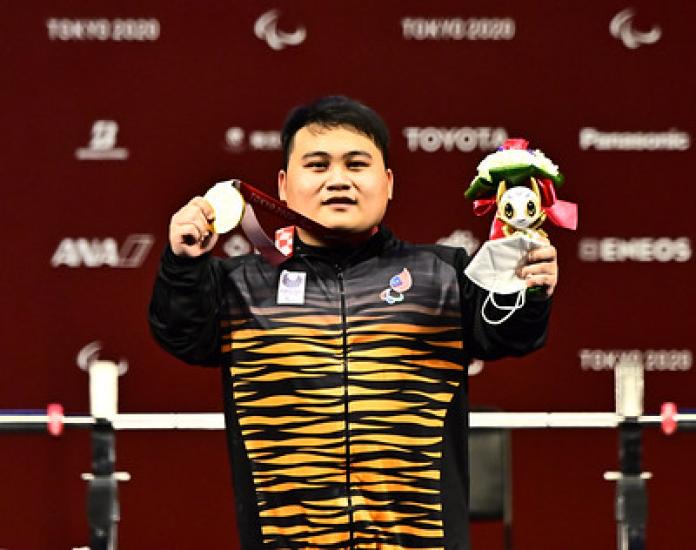 Bonnie Bunyau Gustin holding his gold medal and mascot