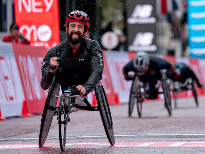 A man celebrates a victory with his fist raised high running in a wheelchair