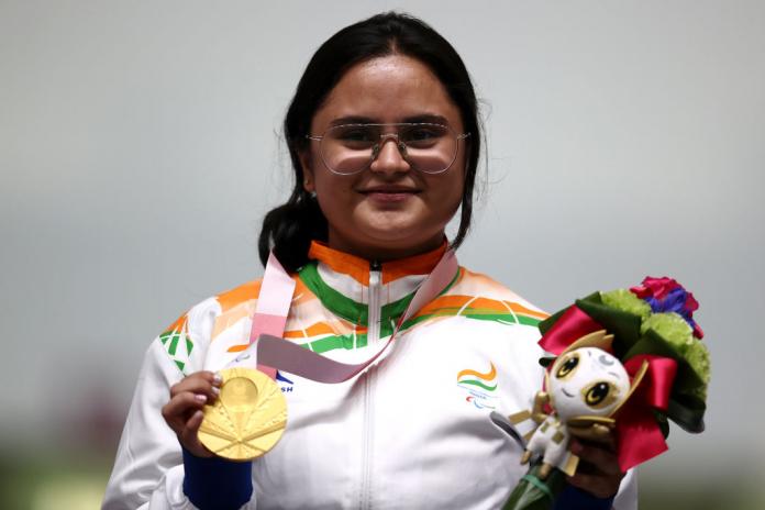 A young woman in the uniform of India posing with a gold medal 