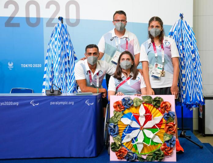 Three members of the Refugee Paralympic Team and their Chef de Mission pose for a photo with Asics gear