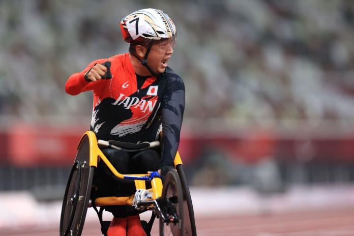 A man in a wheelchair celebrates the victory, putting his fist up