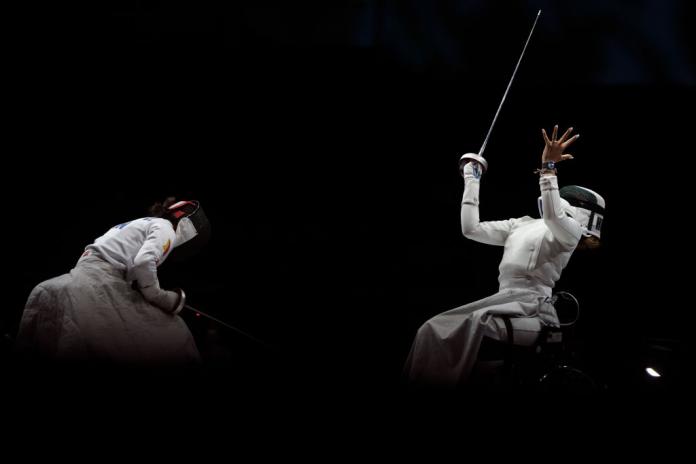 Woman celebrates enthusiastically after winning a wheelchair fencing bout