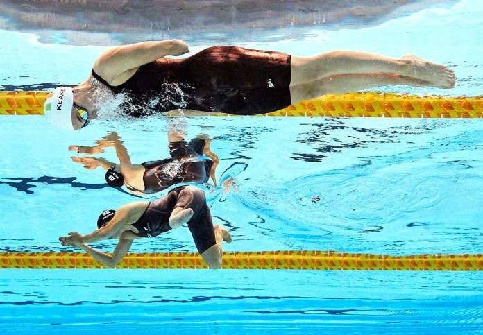 Two women with limb impairments swimming side by side 