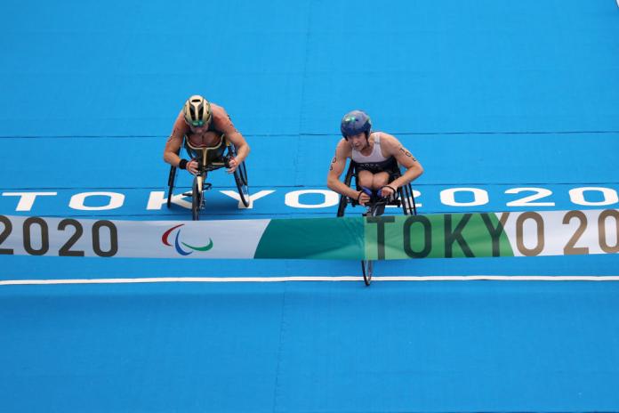 Two female wheelchair racers close to the finish line tape