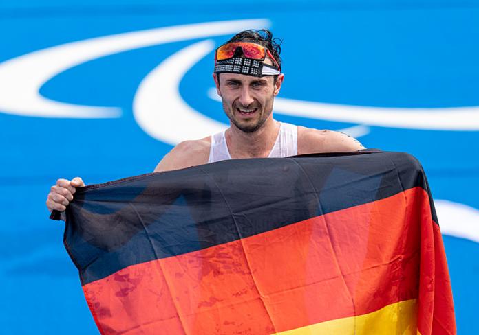 Male triathlete holds German flag