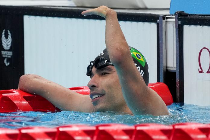 A handless swimmer waving from inside the pool