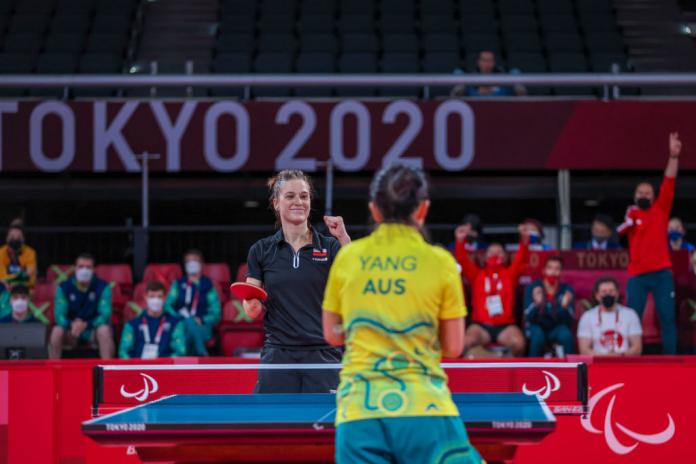 Woman with right arm impairment celebrates point in table tennis