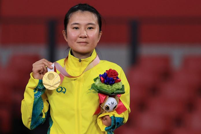 Woman smiles on podium with gold medal