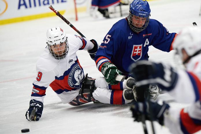 Two male Para ice hockey players chasing the puck 