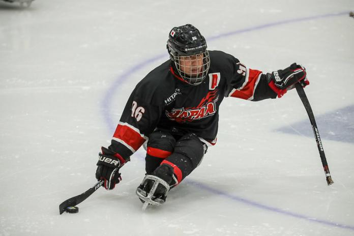 A male Para ice hockey player on ice with the Japanese uniform