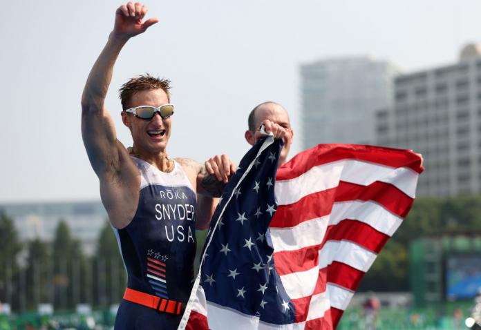 Brad Snyder and guide Greg Billington of Team USA celebrate after crossing the finish line to win the gold in the men's PTVI Triathlon at the Tokyo 2020 Paralympic Games.
