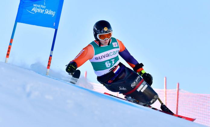 A sit skier going around the gates and skiing down the hill.