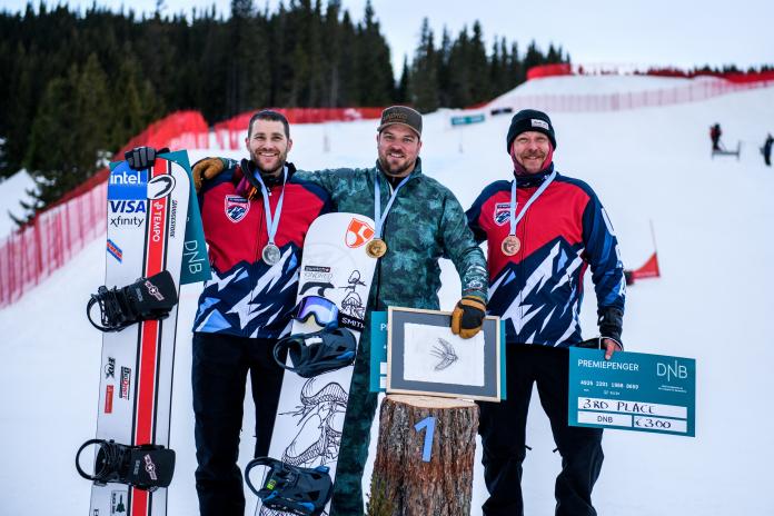 Three male snowboarders in a medal ceremony on the snow