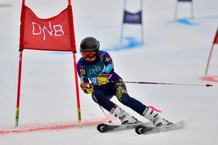 A female Para alpine skier crossing a red gate on a parallel event 