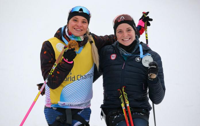 Two smiley women showing their medals in a snow sport competition