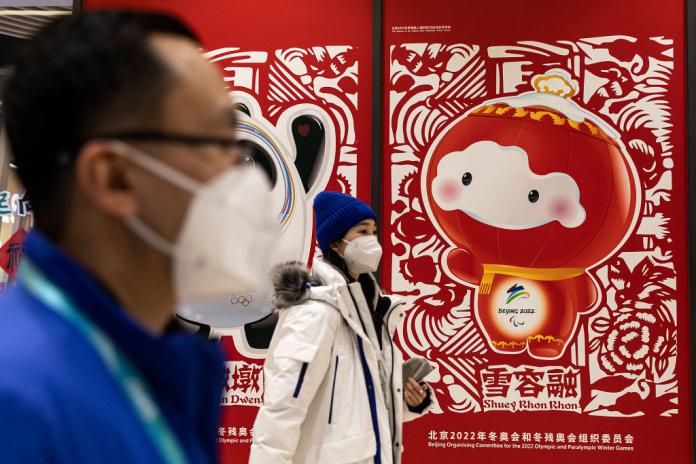 People walk in front of the Beijing Paralympic Winter Games mascot Shuey Rhon Rhon logo in the Paralympic Village.