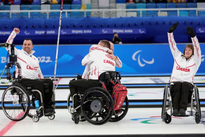 Canadian wheelchair curlers celebrate winning bronze by hugging and raising their arms in the air