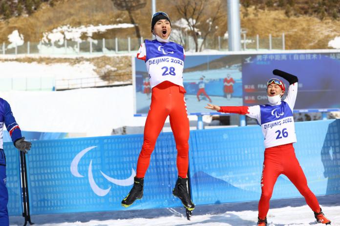Chenyang Wang of China reacts after winning the gold  as compatriot Jiayun Cai looks on following the Men's Middle Distance Free Technique Standing at the Beijing 2022 Paralympic Winter Games at Zhangjiakou National Biathlon Centre. 