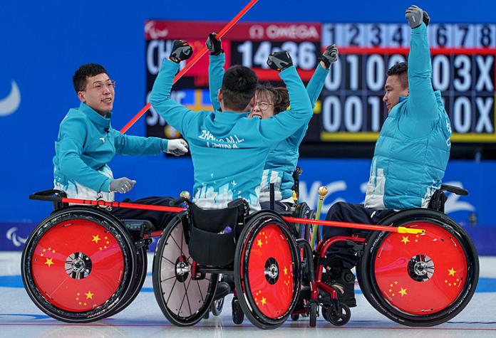 The Chinese wheelchair curling team raise their arms in the air in celebration
