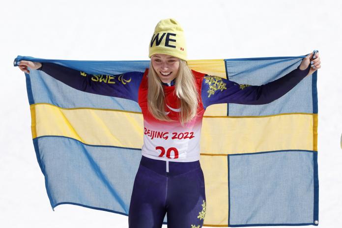 Ebba Aarsjoe celebrates with Swedish flag after winning her second gold at Beijing 2022