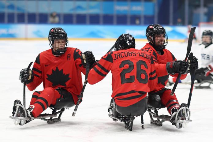 Canada's Para ice hockey players in full gear celebrating a goal.