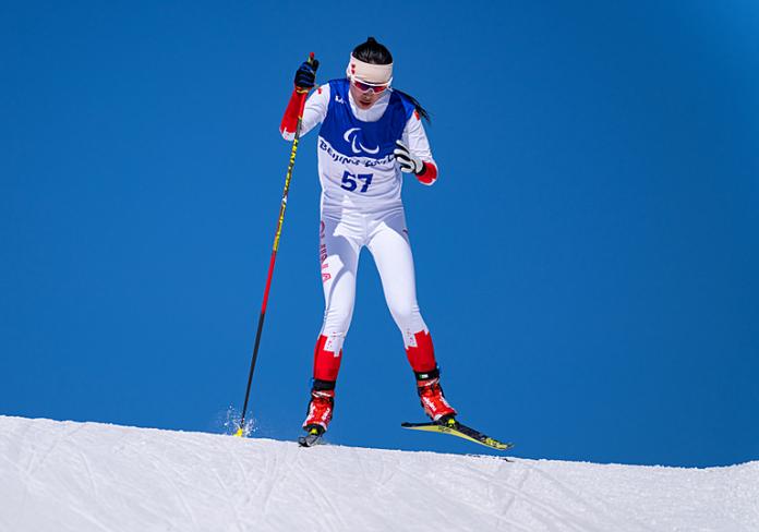 Yujie Guo of China looks determined as she skis in the women's sprint standing in front of clear blue skies